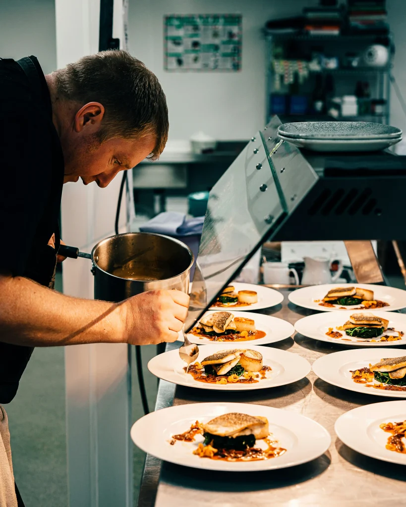 Servicio de catering. Cocinero terminando detalles en plato