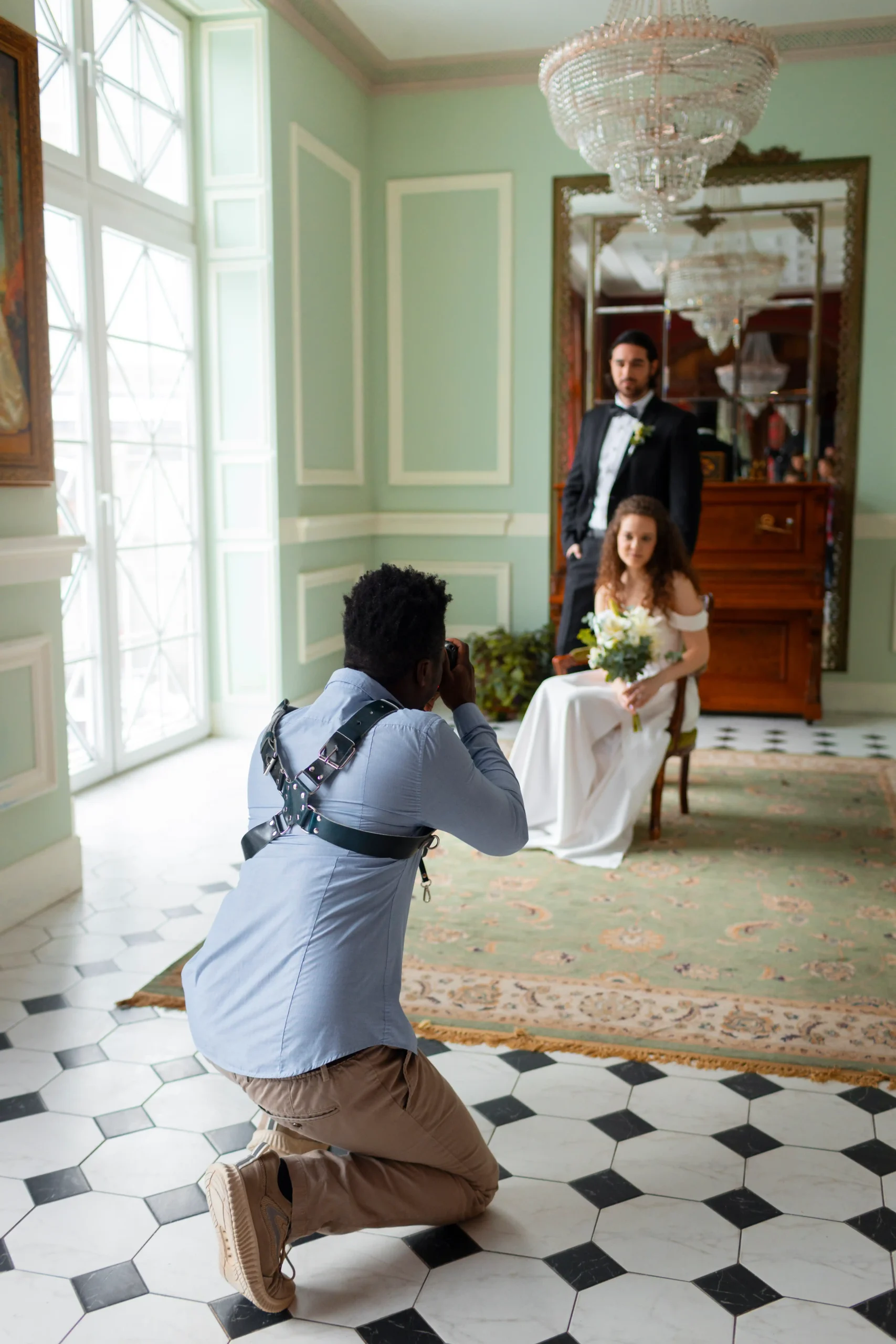 Fotógrafo de cuclillas sacándole foto a una pareja antes de su boda, vestidos de novios.